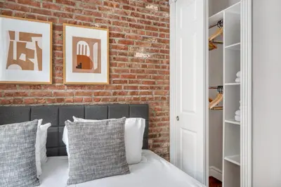 a bedroom with a brick wall and a bed with pillows at East Village 1br w wd nr cafes NYC-1115 in New York
