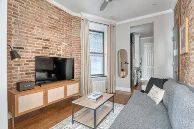 a living room with a brick wall and a tv at East Village 1br w wd nr cafes NYC-1115 in New York