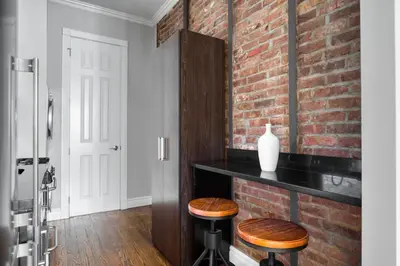 a kitchen with a brick wall and two stools at East Village 1br w wd nr cafes NYC-1115 in New York