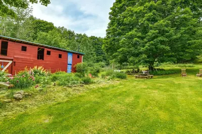 a red building with a picnic table in a yard at Cozy Catskills Vacation Rental with Deck! in Fleischmanns