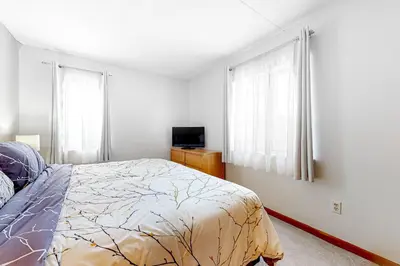 a bedroom with a bed and a tv and windows at Mountain Village #5H in Dover