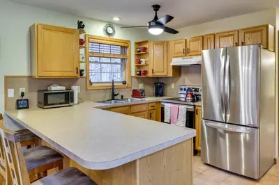 a kitchen with a stainless steel refrigerator and wooden cabinets at Hot Tub, Game Room! Poconos Home 22 Mi to Slopes in Gouldsboro