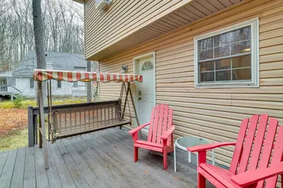 two red chairs and a bench on a porch at Hot Tub, Game Room! Poconos Home 22 Mi to Slopes in Gouldsboro