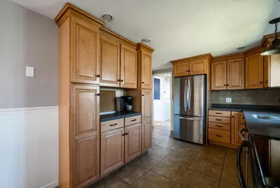 a kitchen with wooden cabinets and a stainless steel refrigerator at Cozy Connecticut Beach House in East Haven