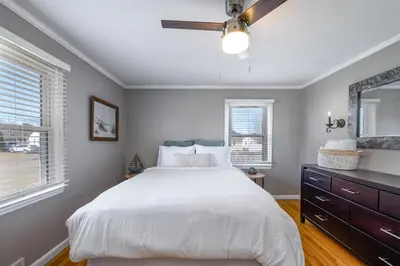 a bedroom with a white bed and a ceiling fan at Cozy Connecticut Beach House in East Haven