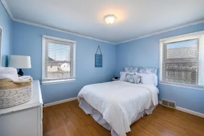a blue bedroom with a bed and two windows at Cozy Connecticut Beach House in East Haven