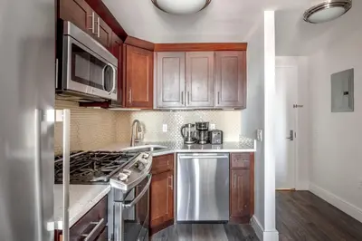 a kitchen with wooden cabinets and stainless steel appliances at UES 2br w wd gym doorman nr Cooper Hewitt NYC-1117 in New York