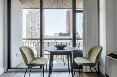 a table and chairs in a room with a balcony at UES 2br w wd gym doorman nr Cooper Hewitt NYC-1117 in New York