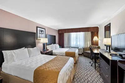 a hotel room with two beds and a desk at Executive Inn - Fort Lee in Fort Lee