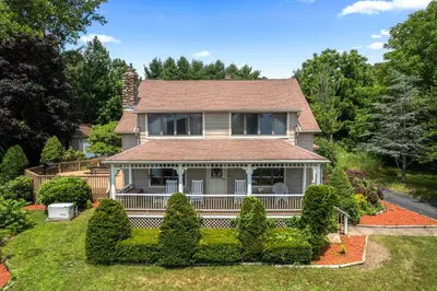 an old house with a porch and bushes at Grammy's Famous Lake House Retreat in East Hampton