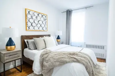 a bedroom with a bed with white sheets and a nightstand at 49-4A Prime Midtown newly 2BR WD in New York