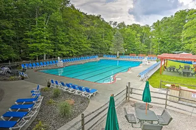 a large swimming pool with blue chairs and tables at Lovely Poconos Cabin with Resort Amenities! in Gouldsboro