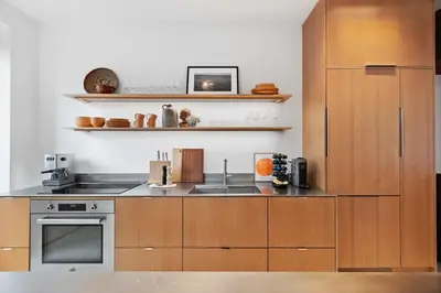 a kitchen with wooden cabinets and a sink at 4BR Greenpoint Duplex Noorman by RoveTravel in Brooklyn