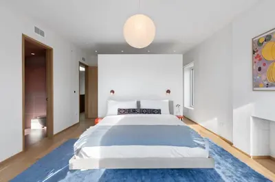 a bedroom with a large bed with a blue rug at 4BR Greenpoint Duplex Noorman by RoveTravel in Brooklyn