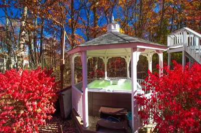 a white gazebo in a garden with red flowers at Stunning Poconos Villa- Hot Tub, Pool, Game Room, BBQ & more in East Stroudsburg