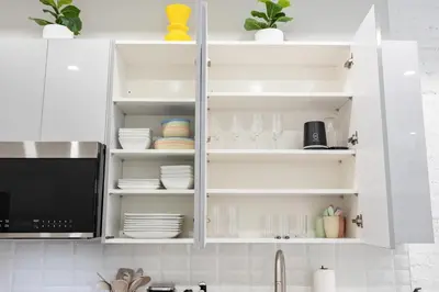 a kitchen with white cabinets with dishes and a microwave at SWJ 1st - Near Most Attractions Walk to Train Times Sq near in New York