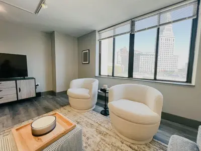 a living room with two chairs and a flat screen tv at Downtown Hartford Condo - XL Center in Hartford