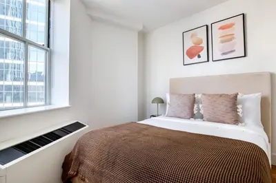 a white bedroom with a large bed and a window at FiDi 1br w lounge gym nr Freedom Tower NYC-1138 in New York