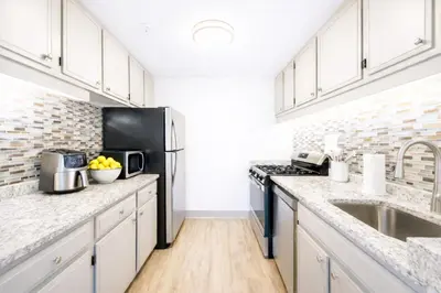 a kitchen with white cabinets and a black refrigerator at The Hartford Skyline - Stylish Downtown Condo with Wifi Gym in Hartford
