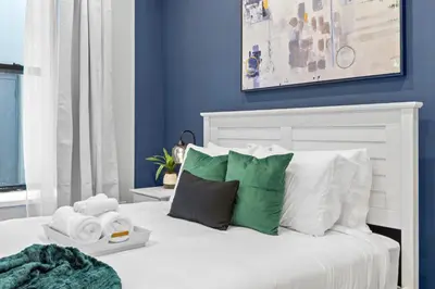 a bedroom with blue walls and a white bed with pillows at SWJ G - Save on 2Day or more Stays 25min to Times Sq in New York