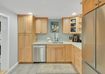 a kitchen with wooden cabinets and a stainless steel refrigerator at Sunset Cove in East Hampton