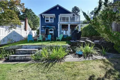 a blue house with chairs in the yard at Sunset Cove in East Hampton