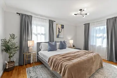 a white bedroom with a large bed with blue pillows at New Beach Home near Stamford Downtown/Shippan in Stamford