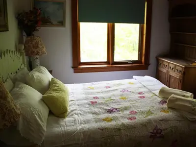 a bedroom with a bed with a blanket on it at Honey Maple Grove BnB in Bedford