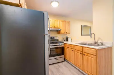 a kitchen with a stainless steel refrigerator and wooden cabinets at Gorgeous Waterfront 2:1 - 2 houses in 1 building. in New Haven