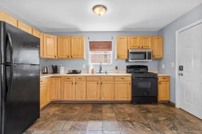 a kitchen with wooden cabinets and a black refrigerator at Gorgeous Waterfront 2:1 - 2 houses in 1 building. in New Haven