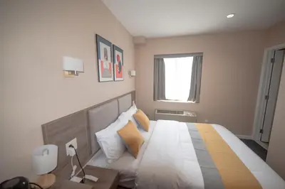 a bedroom with a large bed with yellow and white pillows at Flushing Garden Hotel in Queens