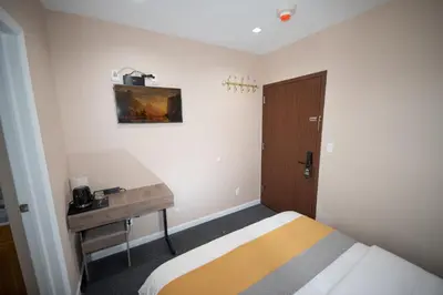 a bedroom with a bed and a desk and a door at Flushing Garden Hotel in Queens