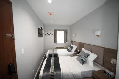 a bedroom with two beds and a window at Flushing Garden Hotel in Queens