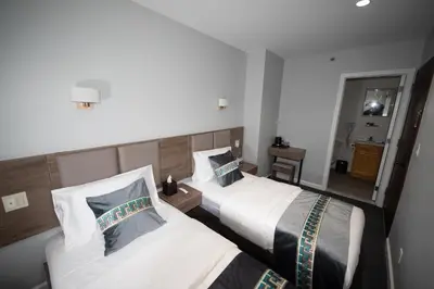 a hotel room with two beds and a mirror at Flushing Garden Hotel in Queens