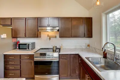 a kitchen with wooden cabinets and a stove top oven at Sleepy Hollow Lake Home with Deck, Pool Access! in Athens