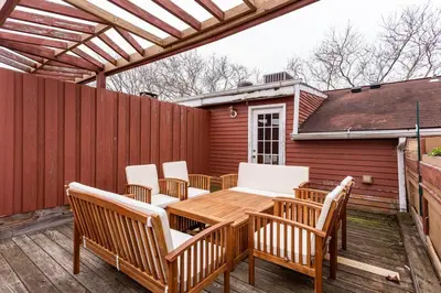 a patio with a wooden table and chairs and a fence at The Brick House at Yale New Haven ( Wooster Square) in New Haven