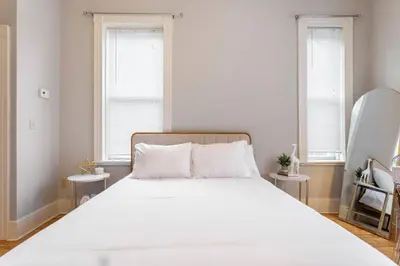 a bedroom with a large white bed with two windows at The Matisse at Wooster Square Yale With Parking in New Haven